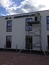 image shows scaffolding and an imagine signs fitter installing L E D letters at high level .